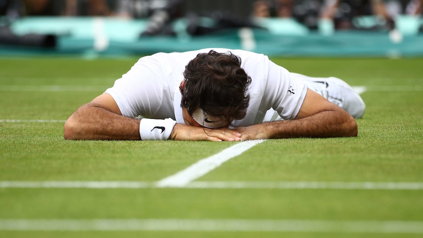 Roger Federer lies injured on the Wimbledon turf