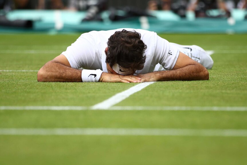 Roger Federer lies injured on the Wimbledon turf