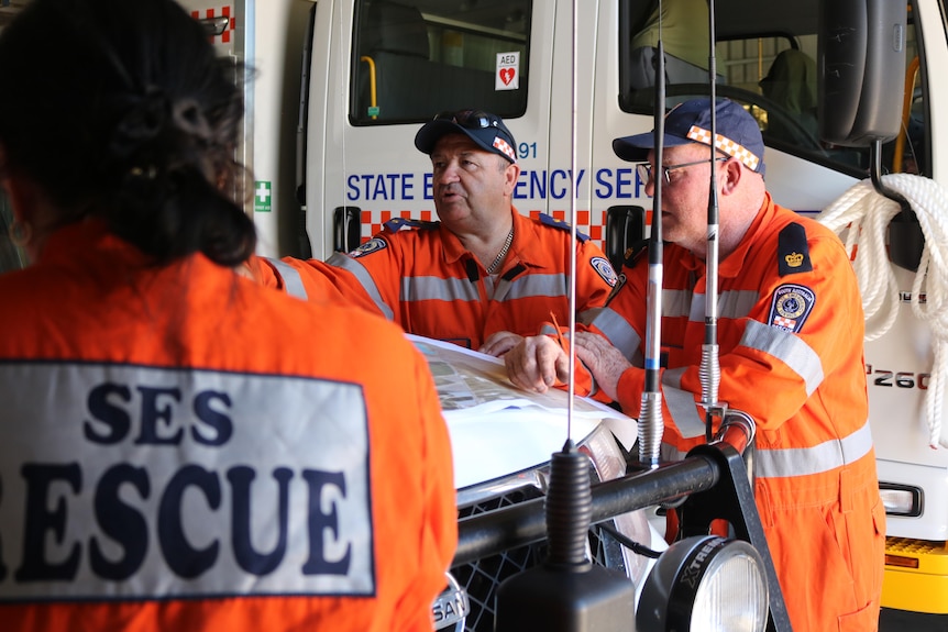 SES volunteers standing around a car talking.