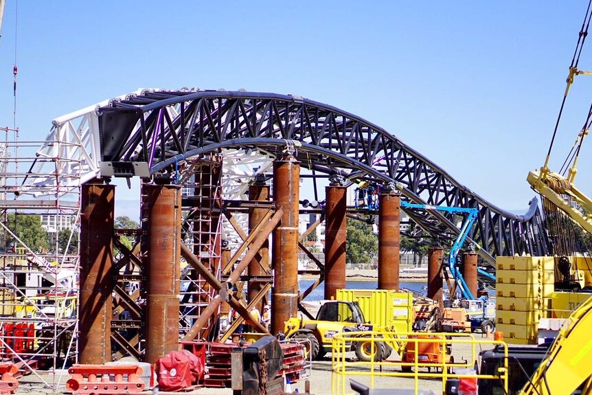 A large arch has been hoisted onto the bridge's support columns.
