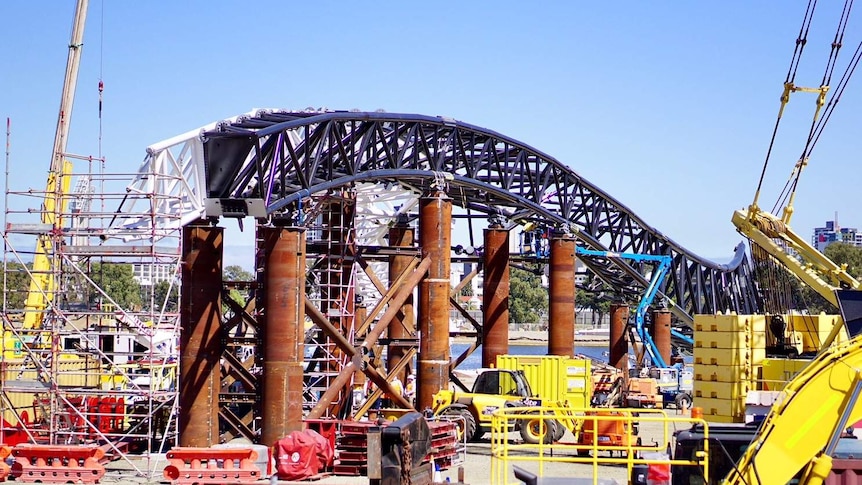 A large arch has been hoisted onto the bridge's support columns.