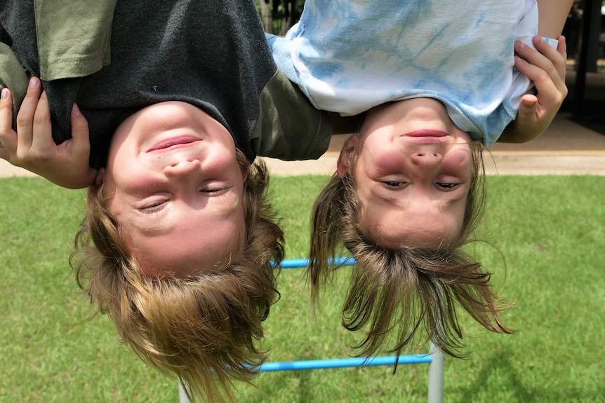 Fynn Goat, 8, and Mir Jung, 7, hanging upside-down from play equipment while on school holidays