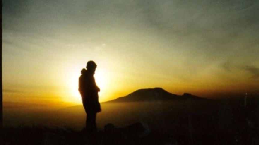 Alan standing atop a mountain, silhouetted by the sun.