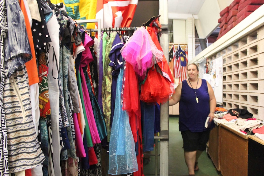 A woman walking near shelves of goods.