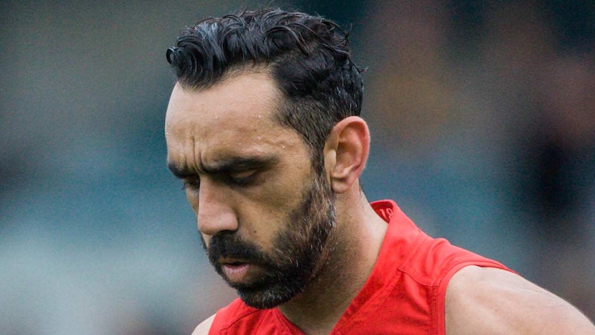 Adam Goodes looks down at the ground as he walks across an oval.