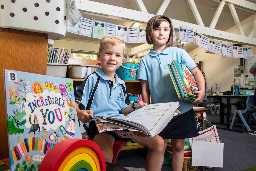 Two young children hold books