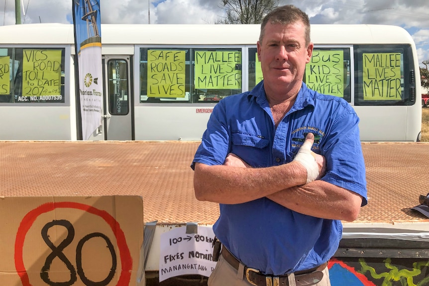 Peter Thompson crosses his arms while standing in front of a bus decorated with protest signs including "Mallee Lives Matter".