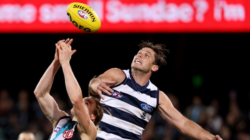 Two AFL players jumping for the ball