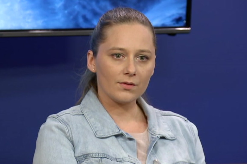 A woman sits in a police conference room answering questions from journalists.