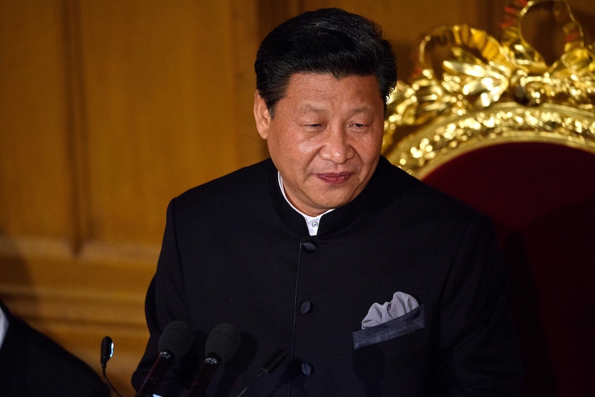 President Xi Jinping of China in a black high collared suit with a cold plated chair behind him.