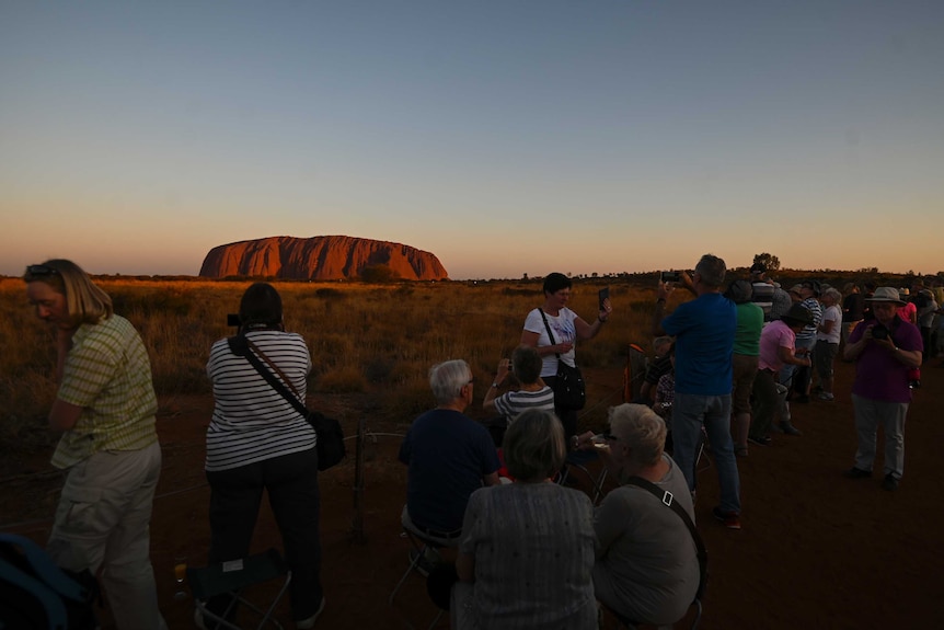 Tourists visit Uluru at sunset