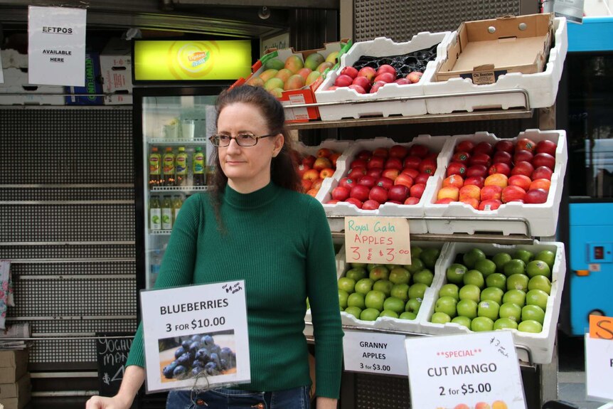 Woman stands in front of fruit stand