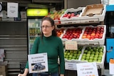 Woman stands in front of fruit stand