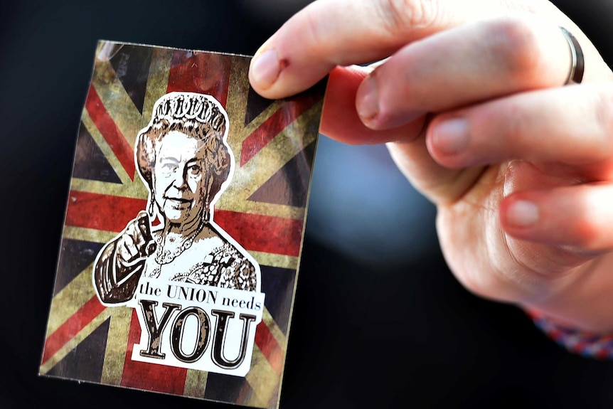 A 'no' vote supporter in Edinburgh, Scotland, holds a sticker depicting an image of Queen Elizabeth II.