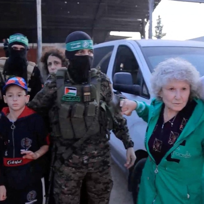 A young boy and a woman surrounded by doctors and militants wearing balaclavas