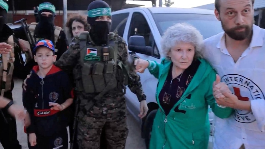 A young boy and a woman surrounded by doctors and militants wearing balaclavas