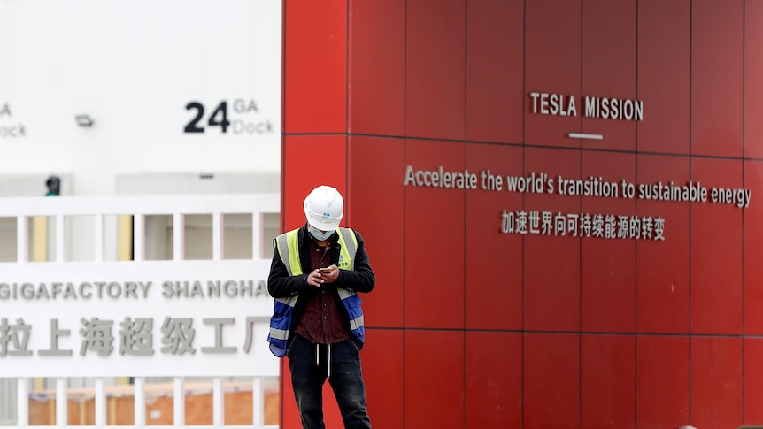 Worker checks his mobile phone outside Tesla's Gigafactory in Shanghai