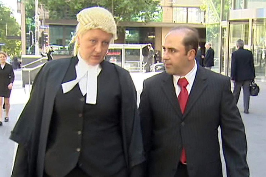 Nicola Gobbo, wearing a lawyers robes and wig walks beside Tony Mokbel outside court.