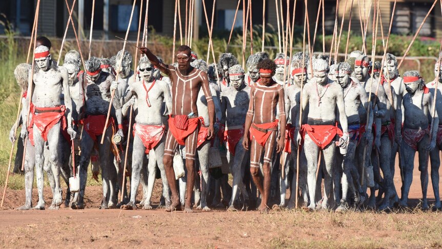 A group of men walk forward at a men's ceremony in Wadeye.