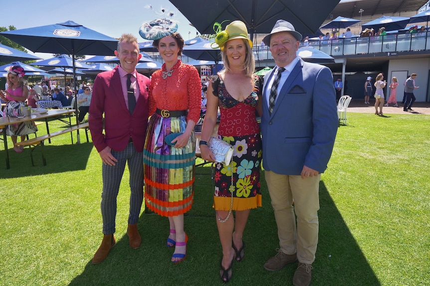 A group of four people dressed up brightly at the Melbourne Cup