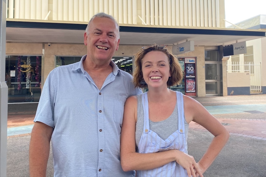 A man and a younger woman, both wearing casual clothes, smile broadly at the camera.