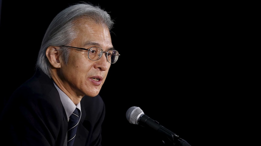 Joji Morishita, wearing a suit and in front of a dark background, speaks.