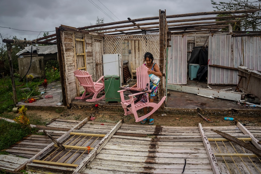 a woman carries a chair from her home which was destoryed and roffless after ian