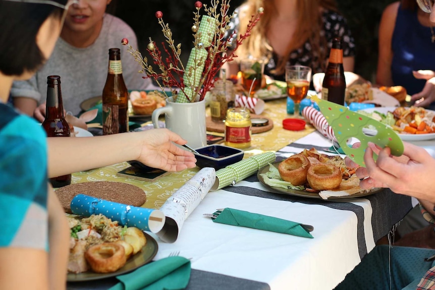 La gente se reúne alrededor de la mesa para el almuerzo de Navidad