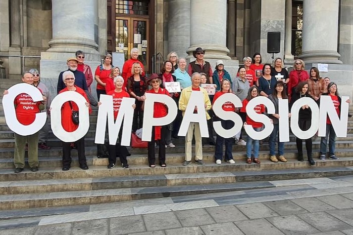 Euthanasia advocates standing on the steps of South Australia's Parliament House with a sign saying "compassion"