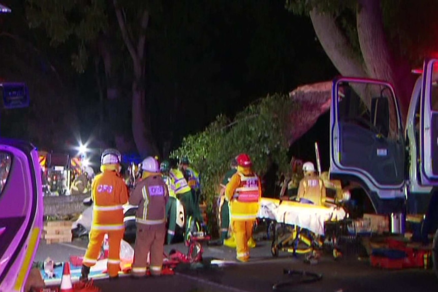 A large tree limb on top of a car with emergency crew standing by.