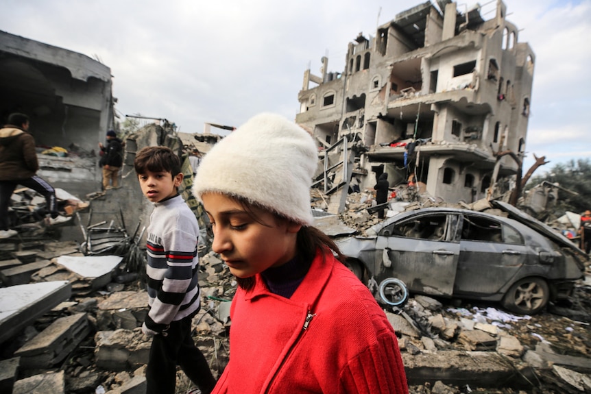 Two children walk past rubble at a refugee camp in central Gaza strip