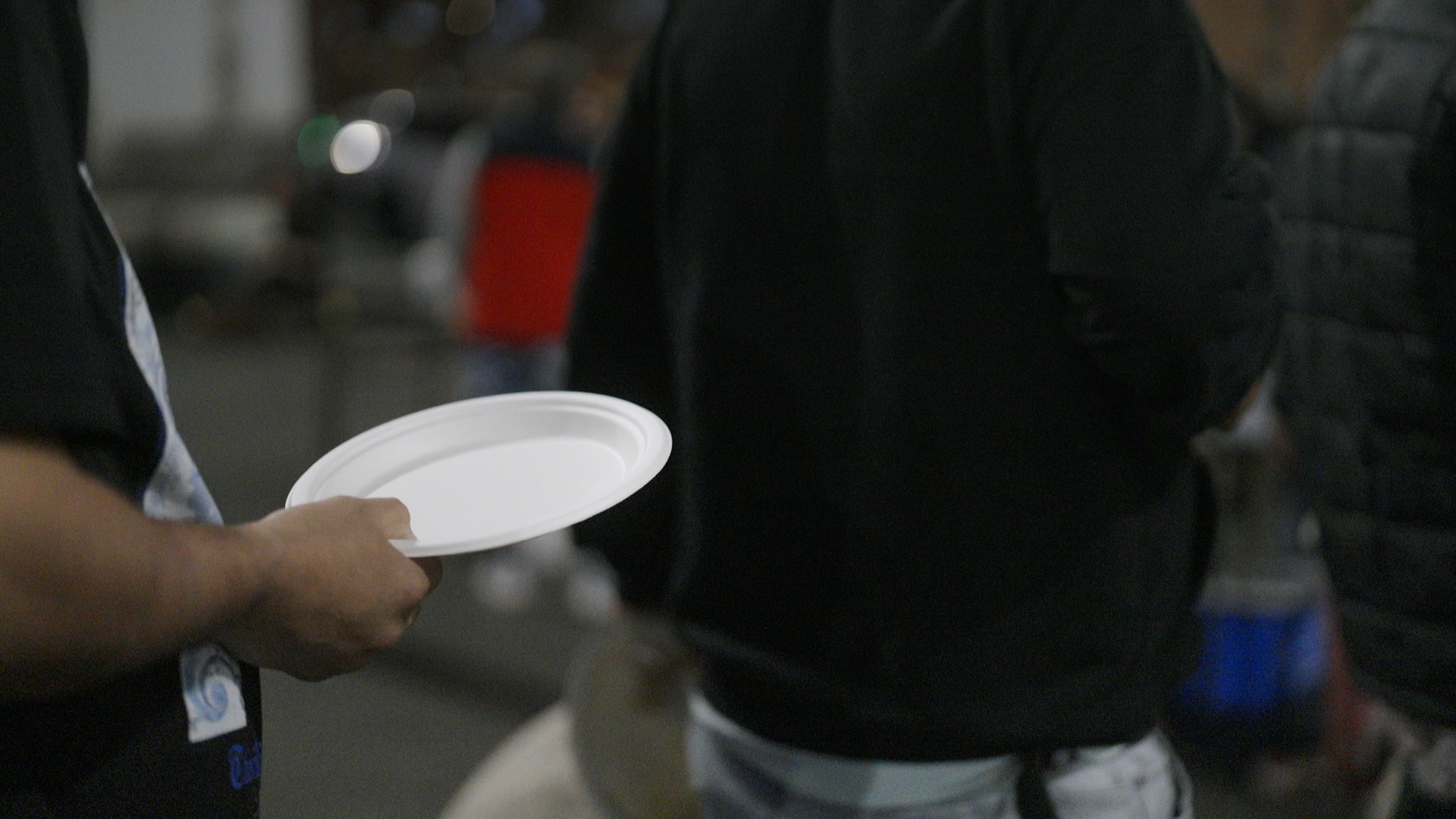 A man holding a plate in a queue.