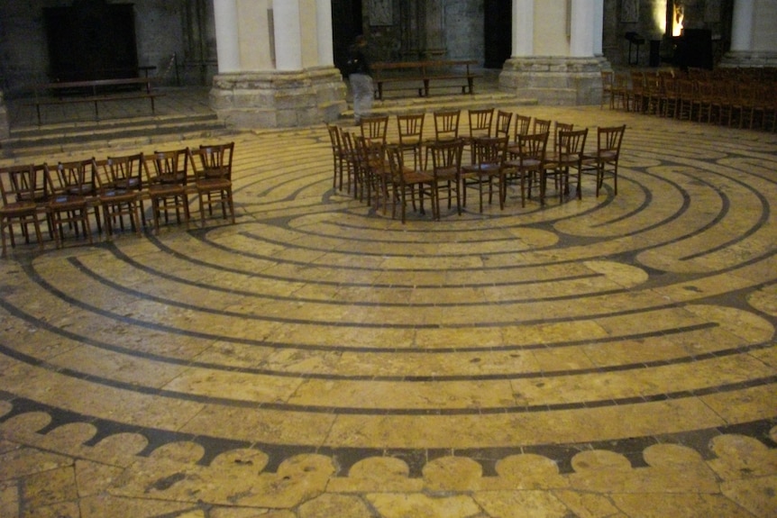 A floor designed like a labrynth with a group of chairs sitting at its centre