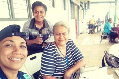 Tres mujeres de Fiji se sientan juntas y sonríen a la cámara.