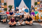 18 participants of sit on chairs and couches smiling for photo
