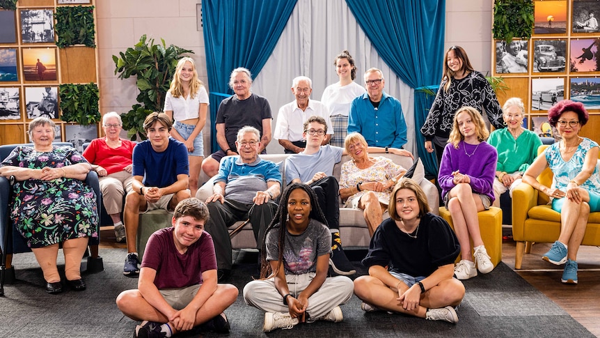 18 participants of sit on chairs and couches smiling for photo