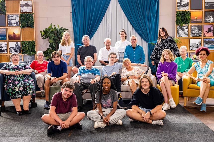 18 participants of sit on chairs and couches smiling for photo