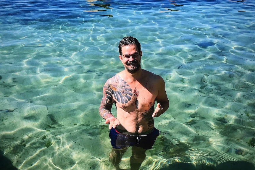 Ben Jenkins smiling while standing in a clear turquoise ocean pool.