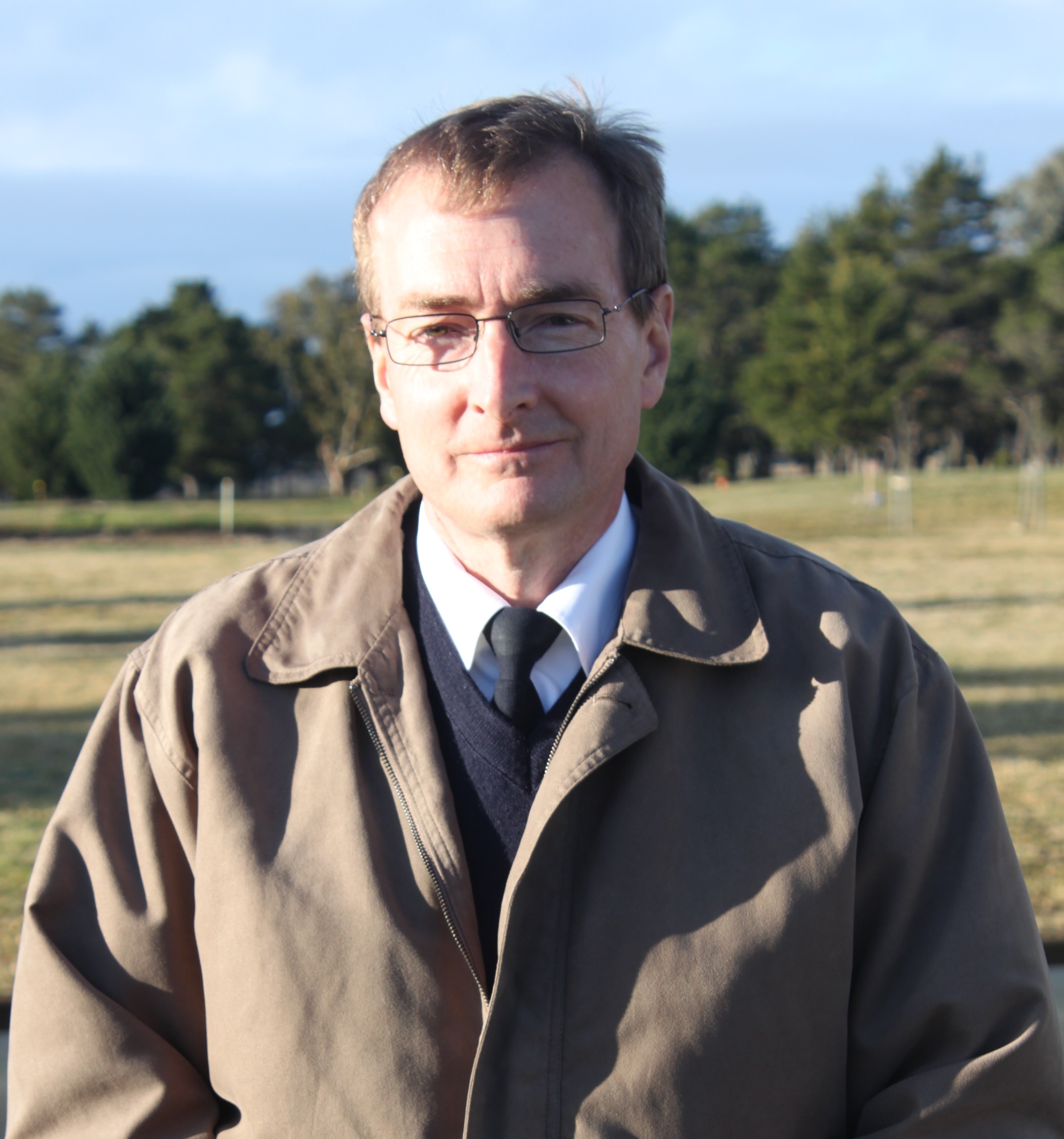 Man in a brown jacket over sweater and tie