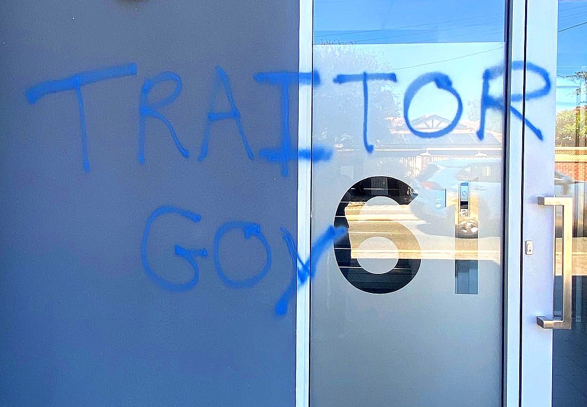Las palabras “traidor” y “goy” están pintadas con spray en una pared azul.