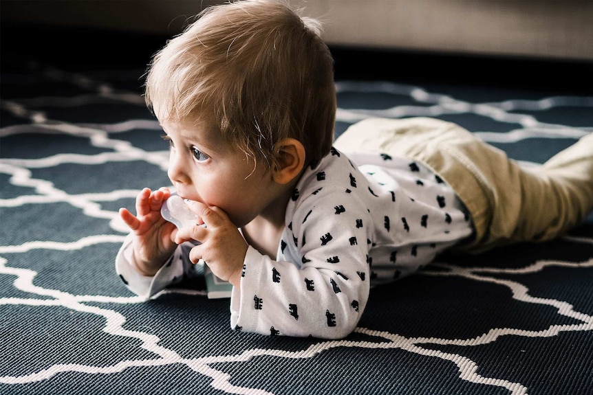 Cute crawling baby sucking on a dummy for a story about why parents are choosing masculine names for their girls.