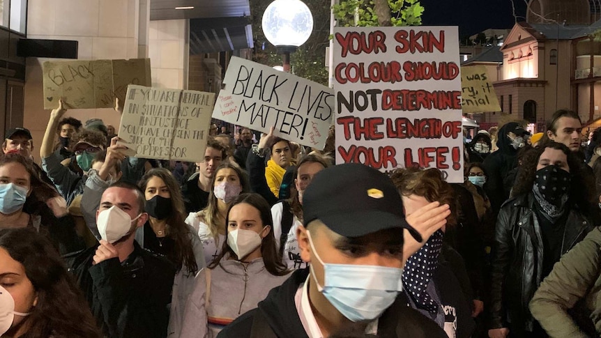 People wearing masks holding up placards during a Black Lives Matter protest in Sydney.