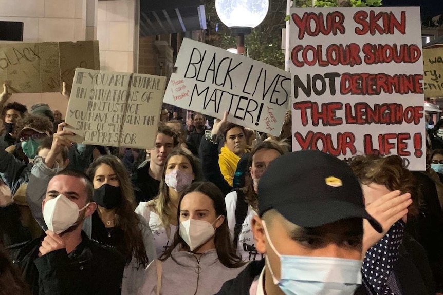 People wearing masks holding up placards during a Black Lives Matter protest in Sydney.