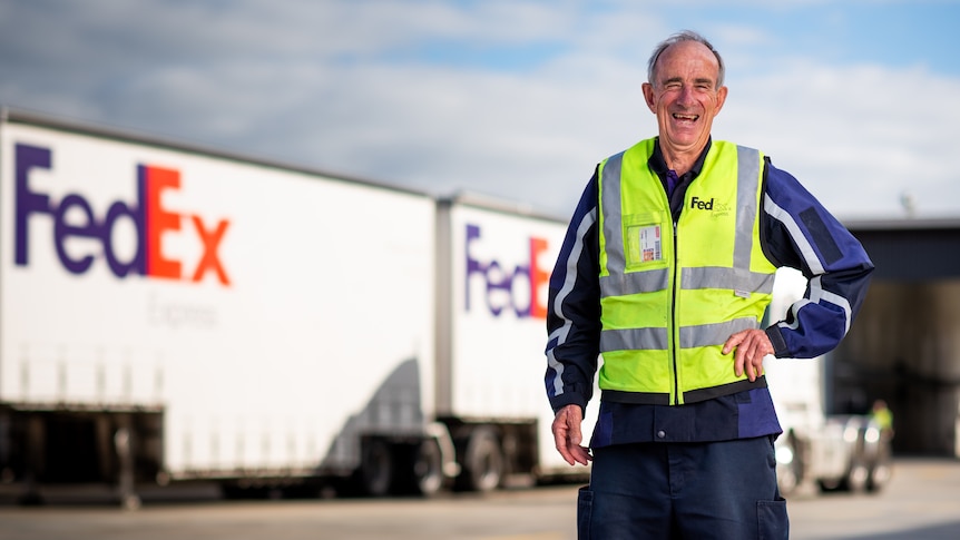 Barry Foreman smiles in front of a Fedex warehouse