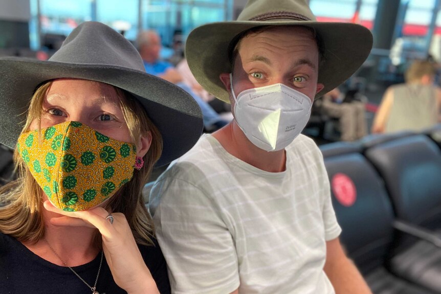 Sophia O'Rourke and Matt Bamford sit at Sydney Airport wearing their masks.