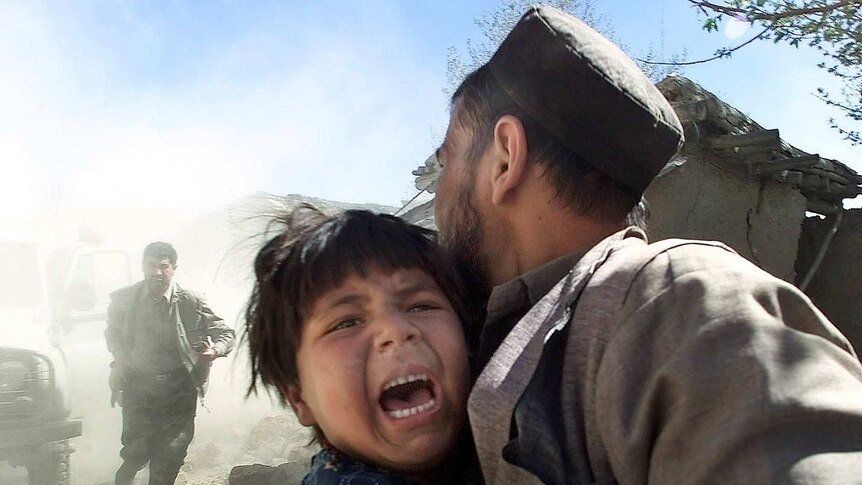 An Afghan girl screams as she is held her father as a sharp aftershock