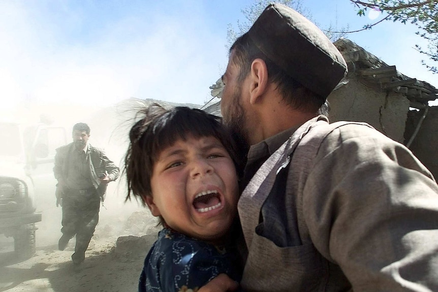 An Afghan girl screams as she is held her father as a sharp aftershock
