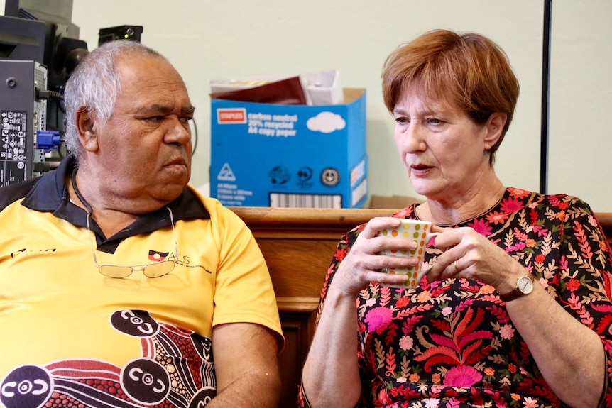 A man and a woman sitting down, talking.