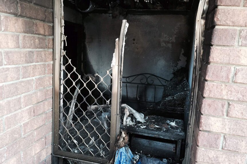 A look inside the burnt-out bedroom of a Camillo house, with thewindow broken and furniture destroyed.