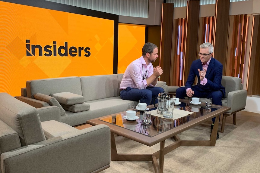 Clark and Speers sitting on couch and chair with yellow Insiders logo on screen behind them.